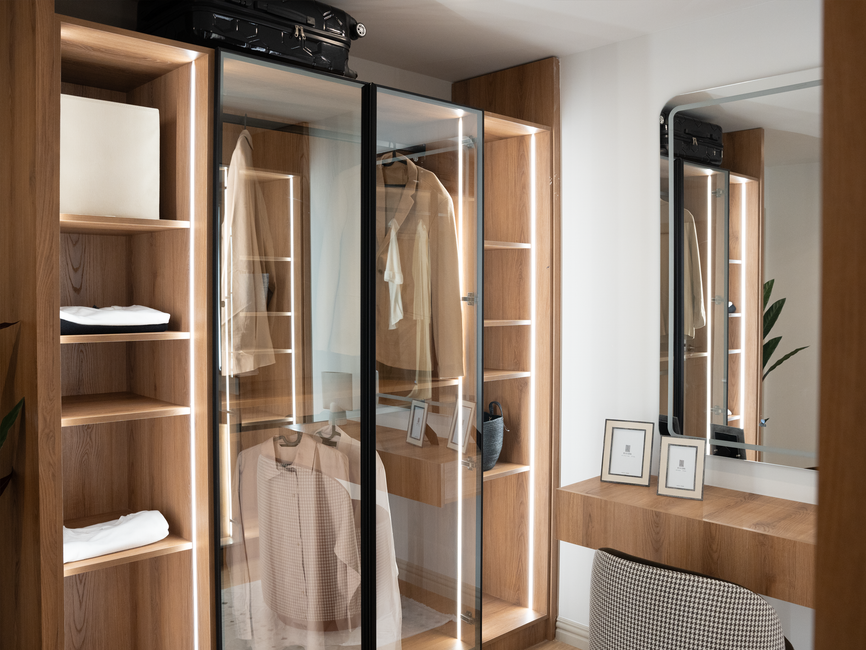 Elegant minimalist wardrobe with glass doors and wooden shelves, showcasing contemporary interior design.