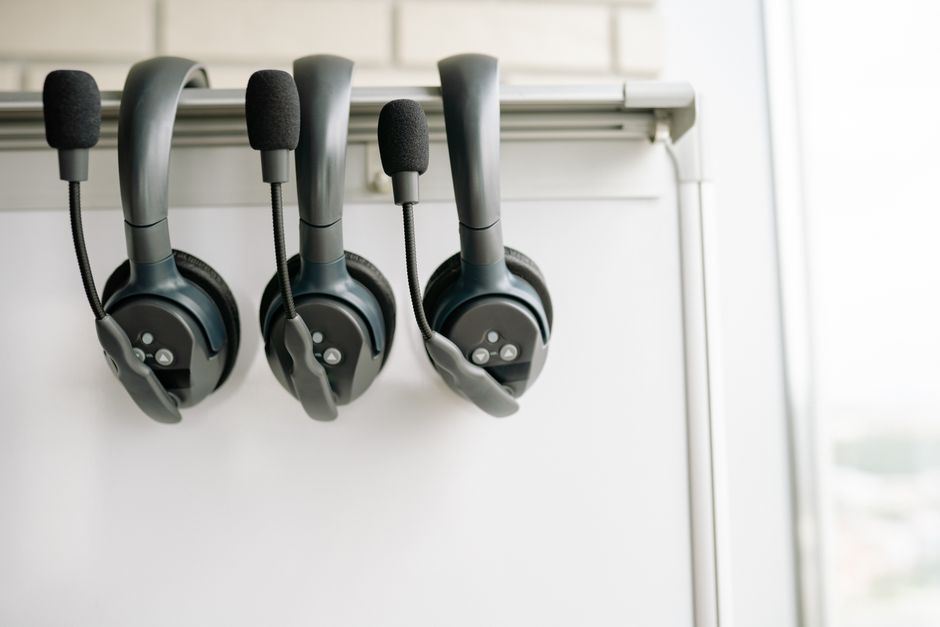 Three black headsets neatly organized on a whiteboard hook, emphasizing tech and communication.