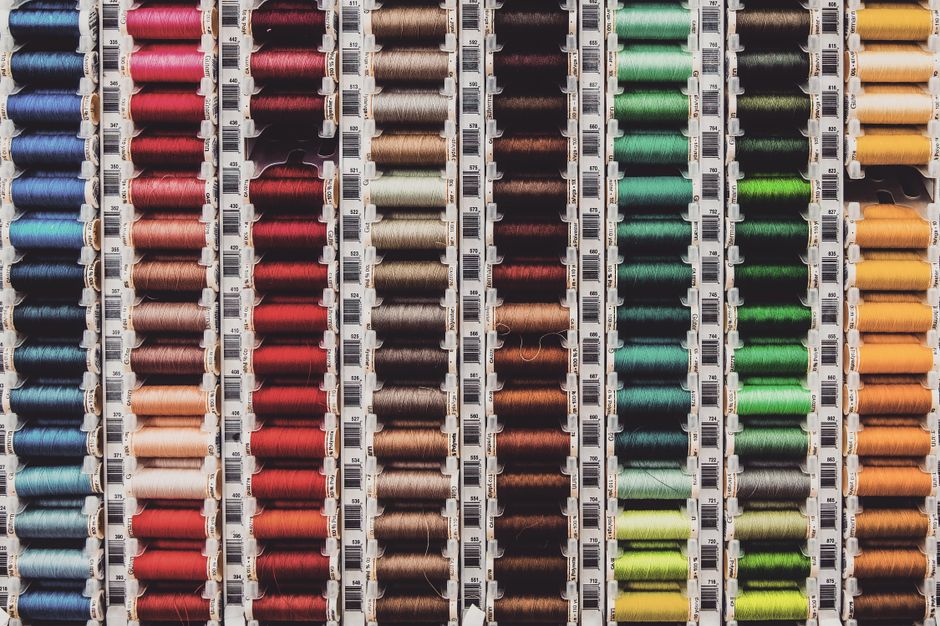 A vibrant array of colored thread spools neatly organized in rows, perfect for sewing enthusiasts.